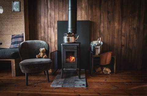Acogedora cabaña de madera en el bosque de Limburg, Bélgica, con estufa, sillón y osito.