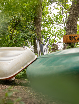 Dos canoas reposan junto a un cartel de madera que dice 'Boothuys', rodeadas de vegetación en Ruysbos.