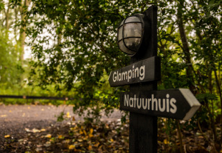 Skilt med retninger til Glamping og Naturhus, omgivet af grønt, i Buitengoed Ruysbos, Gelderland.