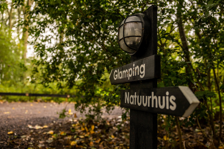 Signpost for Glamping and Nature House, surrounded by lush greenery at Buitengoed Ruysbos, Gelderland.