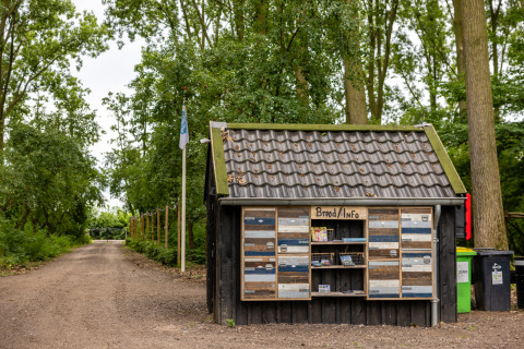 Small info shed labeled 'Brood/Info' beside a rural path surrounded by trees at Ruysbos in Gelderland, Netherlands.