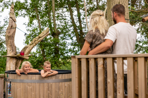 Familia disfrutando al aire libre en Buitengoed Ruysbos, Gelderland, niños relajándose en un jacuzzi exterior.
