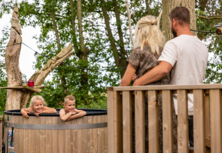 Family enjoying outdoor time at Buitengoed Ruysbos holiday park in Gelderland, kids relaxing in a hot tub.