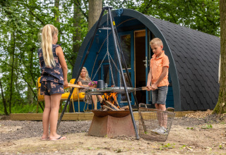 To børn laver mad over bål foran en campinghytte i Buitengoed Ruysbos, Gelderland, Holland.