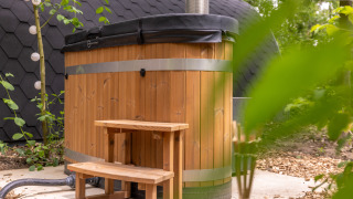 Bañera de hidromasaje exterior de madera con tapa y escalera en Buitengoed Ruysbos, Gelderland, Países Bajos.