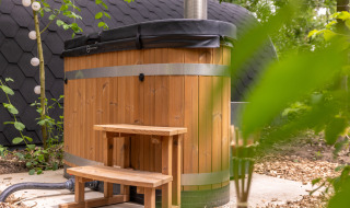 Bañera de hidromasaje exterior de madera con tapa y escalera en Buitengoed Ruysbos, Gelderland, Países Bajos.