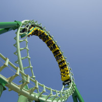 Montaña rusa haciendo un loop en parque vacacional con glamping, cielo despejado y pasajeros emocionados.