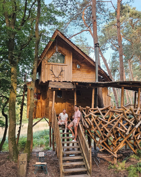 Dos hombres sentados en las escaleras de una cabaña de madera en Cosy Cabins, bosque de Limburg, Bélgica.