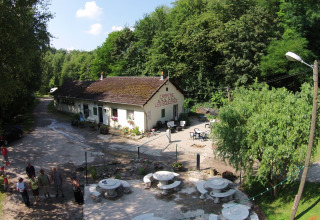 Vue aérienne du Camping Les Bouleaux, parc de vacances à Grand Est, France, entouré de forêt et de visiteurs.