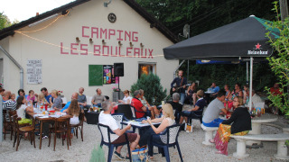 Camping Les Bouleaux en Grand Est, Francia, con personas disfrutando bebidas, música y ambiente al aire libre.