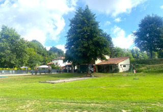 Blick auf Moulin du Pommier Glamping & Camping in Nouvelle-Aquitaine, Frankreich, mit viel Grün und Gebäuden.