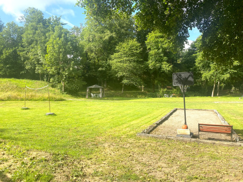 Groen grasveld met een sportveld, badmintonnet, basketbalring en tuinhuisje bij Moulin du Pommier Glamping & Camping.