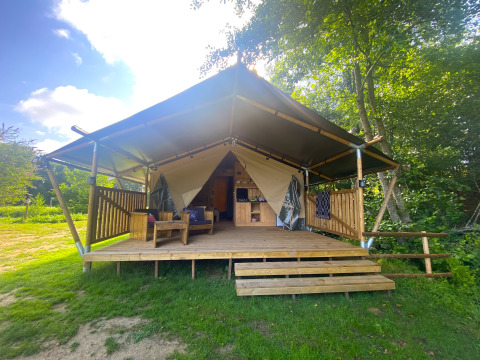 Safari-Zelt mit Holzterrasse und Sitzgelegenheiten bei Moulin du Pommier Glamping & Camping in Frankreich.