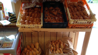 Pan fresco y croissants expuestos en un estante de madera en Camping Les Bouleaux, Grand Est, Francia.