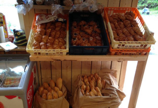 Pane fresco e croissant esposti su uno scaffale di legno a Camping Les Bouleaux, Grand Est, Francia.
