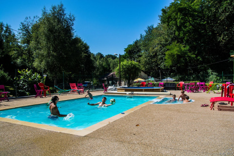 People enjoy the outdoor swimming pool at Camping Les Bouleaux holiday park, Grand Est, France on a sunny day.