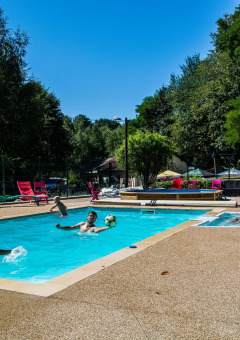 Personas disfrutan de la piscina al aire libre en Camping Les Bouleaux, Grand Est, Francia, rodeadas de naturaleza.