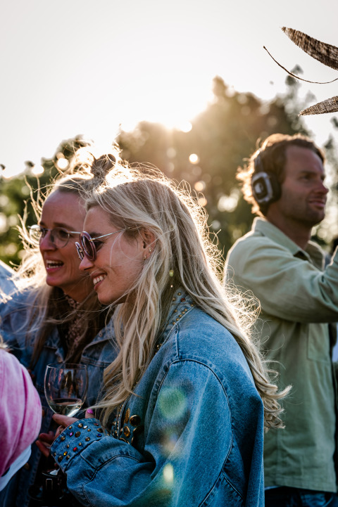 Mensen genieten van een zonnige dag op TinyParks Cast Away in Zuid-Holland, Nederland, met wijn en muziek.