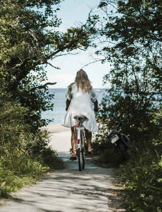 Mujer en bicicleta por el bosque hacia la playa