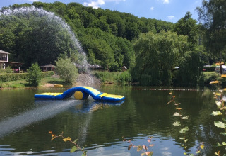 Opblaasbare waterattractie op een meer bij Camping Donnersberg, omgeven door groene bossen in Duitsland.