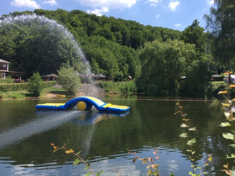 Opblaasbare waterattractie op een meer bij Camping Donnersberg, omgeven door groene bossen in Duitsland.
