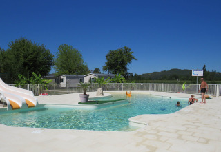 Buitenzwembad met waterglijbaan en mensen, gelegen in Camping la Salvinie, Nouvelle-Aquitaine, Frankrijk.