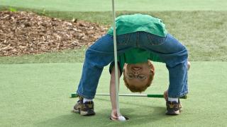 Un niño se queda boca abajo en un campo de minigolf