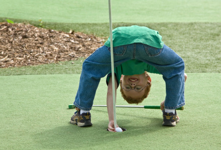 Un niño se queda boca abajo en un campo de minigolf
