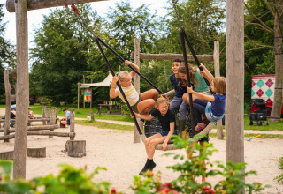 Kinderen spelen samen op een schommel in een speeltuin bij Sandberghe vakantiepark in Noord-Brabant, Nederland.