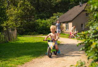 Een klein jongetje fietst zonder shirt op een paadje bij een vakantiehuis in Sandberghe, Noord-Brabant.