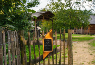 Houten hek met bord bij Sandberghe vakantiepark in Noord-Brabant, Nederland, omgeven door groen.