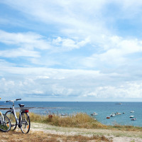 Fietsen geparkeerd aan zee met uitzicht op boten bij Ploemeur in Bretagne, Frankrijk, onder een blauwe lucht.