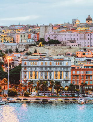 Vista panorámica de Cannigione, Cerdeña, Italia, con edificios coloridos y barcos atracados en el puerto.