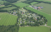 Luchtfoto van Camping de Meibeek, een vakantiepark omringd door groene velden in Gelderland, Nederland.