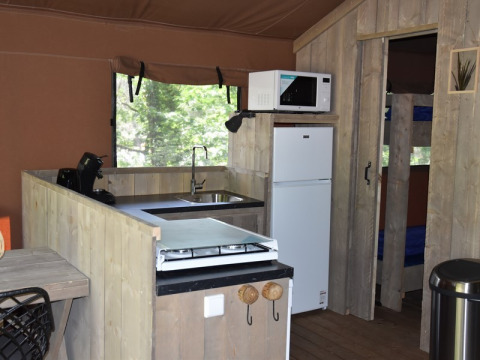 Vista interior de la cocina en Veluwe Lodge en Camping Samoza, Holanda, con nevera, microondas y estufa.