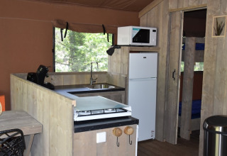 Vista interior de la cocina en Veluwe Lodge en Camping Samoza, Holanda, con nevera, microondas y estufa.