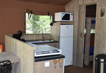 Vista interior de la cocina en Veluwe Lodge en Camping Samoza, Holanda, con nevera, microondas y estufa.