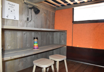 Interior de Veluwe Lodge en Camping Samoza, Países Bajos, con escritorio de madera y taburetes.