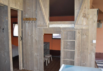 Interior de la Veluwe Lodge en Camping Samoza, Países Bajos, con cama elevada, muebles de madera y ambiente acogedor.