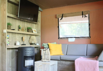 Sala con sofá gris, TV y estufa en Veluwe Lodge de Camping Samoza, Países Bajos.