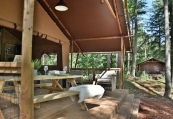 Terraza de madera en Veluwe Lodge de Camping Samoza rodeada de bosque en los Países Bajos.