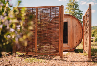 Outdoor wooden sauna and privacy screen beside safari tent at Camping Donnersberg, Germany, in summer.