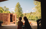Two people enjoy the view from a safari tent with sauna at Camping Donnersberg, surrounded by greenery.