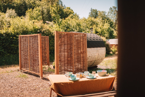 Outdoor area of safari tent with sauna and set dining table at Camping Donnersberg, Germany.