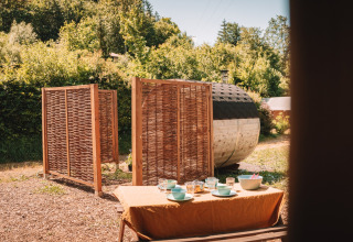 Outdoor area of safari tent with sauna and set dining table at Camping Donnersberg, Germany.