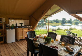 Interior view of Safari tent of Excellent Maaszicht at Camping de Boomgaard in Belgium with lake scenery.