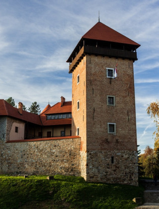 Eine historische Burg in Bosiljevo bei Karlovac, Kroatien, umgeben von Herbstbäumen und blauem Himmel.