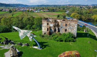 Militärausstellung mit Flugzeug und zerstörtem Gebäude nahe Bosiljevo, Karlovac, Kroatien, an einem grünen Platz.