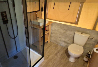Moderne badkamer in een safaritent bij Mooirust, Nederland, met douche, wastafel en toilet.