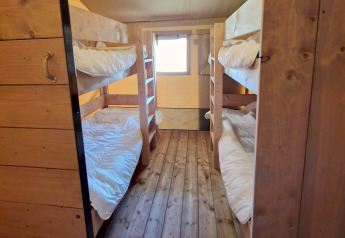 Slaapkamer met houten stapelbedden en witte dekens in een Safari tent bij Mooirust, Nederland.
